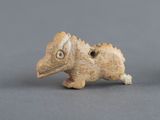 une petite figurine représentant un oiseau posée sur une surface grise