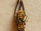 a necklace with a gold vase on it hanging from a chain