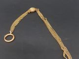 a close up of a gold chain bracelet with a circular clasp