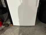 a white refrigerator and a black trash can in a room