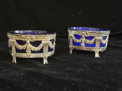 une paire de bols en verre argenté et bleu posés sur des socles, sur fond noir