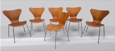 six chaises en bois aux pieds métalliques alignées contre un mur blanc