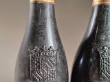two bottles of wine sitting next to each other on top of a wooden table