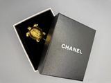 Broche « tortue » Chanel dans un écrin noir sur fond blanc
