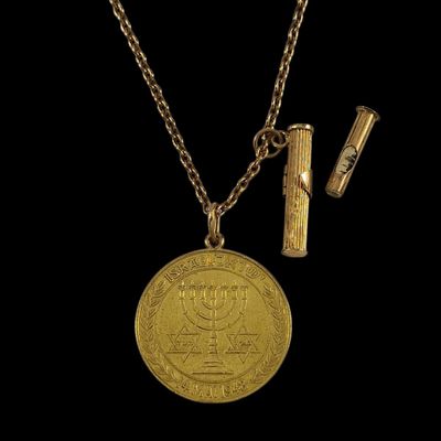 une pièce d'or, un briquet et un collier sur fond noir
