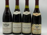 quatre bouteilles de vin sont alignées sur une surface blanche