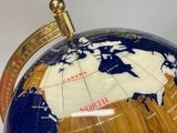 a close up of a globe on a table with a coin