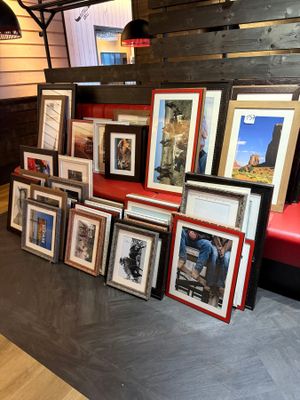a lot of framed pictures on the floor of this room