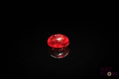 a close up of a red glass object on a black surface