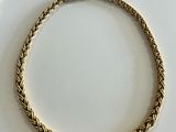 a close up of a gold necklace on a white surface