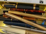 many different pens in a box on a table