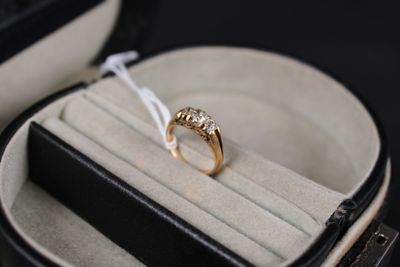 a gold ring in a black case with a white ribbon