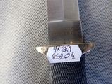 a knife with a tag attached to it sitting on a piece of cloth