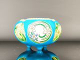 un vase bleu orné d'un motif vert et jaune