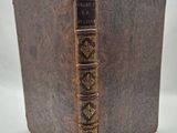 an old book with a brown cover sitting on top of a white table