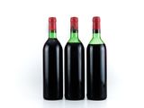 three bottles of wine are lined up in a row on a white surface