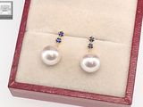 pair of pearl and sapphire earrings in a box on a white surface