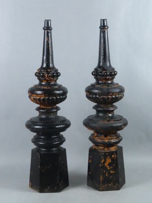 pair of black and gold candlesticks on pedestals against a gray background