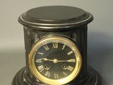 a black clock with roman numerals sitting on a table