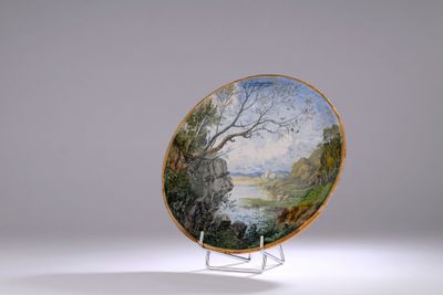 une assiette décorée d'une peinture, posée sur un socle