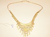 a close up of a gold necklace on a white surface