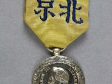 un gros plan d'une médaille posée sur une surface blanche, avec un ruban doré