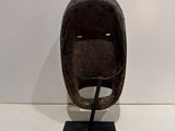 sculpture of a wooden helmet on a metal stand on a white surface