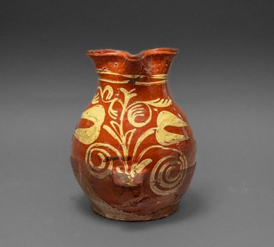 un vase rouge orné de motifs dorés sur un fond gris