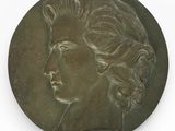 une vieille médaille en bronze sur laquelle est représenté le visage d'une femme