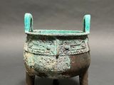 an old bronze pot with a green handle on a stand
