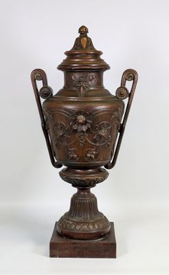 une image représentant une grande urne en bronze posée sur un socle en bois