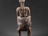 une statue représentant un squelette assis sur une chaise en bois