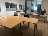 des tables et des chaises dans une pièce avec une grande fenêtre en arrière-plan