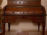 a wooden desk with drawers and a vase on the table