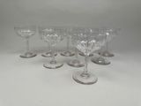 six glass goblets are lined up on a white surface