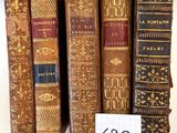 Plusieurs vieux livres sont alignés sur une étagère, accompagnés d'une étiquette de prix