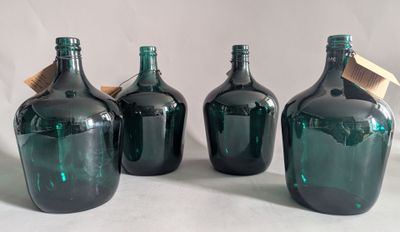 three green glass bottles with a wooden stopper sit on a white surface