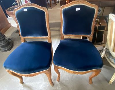 une paire de fauteuils en velours bleu, avec des bordures dorées et des pieds en bois