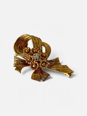 une image représentant une broche de couleur dorée ornée d'un nœud