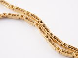 a close up of a gold necklace with a chain on a white surface