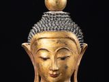 une image représentant une tête de Bouddha en or posée sur un socle en marbre