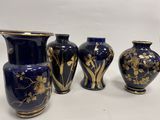 quatre vases bleus ornés de motifs dorés sont alignés sur une surface blanche