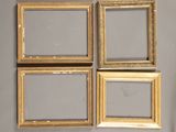 quatre cadres dorés sur un mur gris, avec un miroir