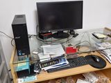 a computer desk with a monitor, keyboard, mouse, and other items on it