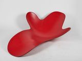 un objet rouge posé sur une surface blanche, avec un fond blanc
