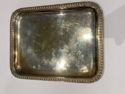 a silver tray on a wall with a mirror above it
