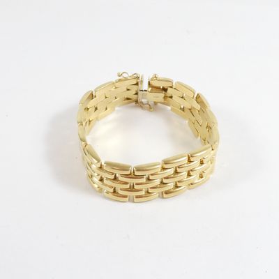 gros plan d'un bracelet en or sur une surface blanche
