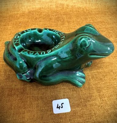 une grenouille verte assise sur une table sur laquelle se trouve une étiquette de prix