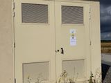 two doors on the side of a building on the side of the road