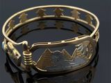 un gros plan d'un bracelet en or orné d'un paysage de montagne